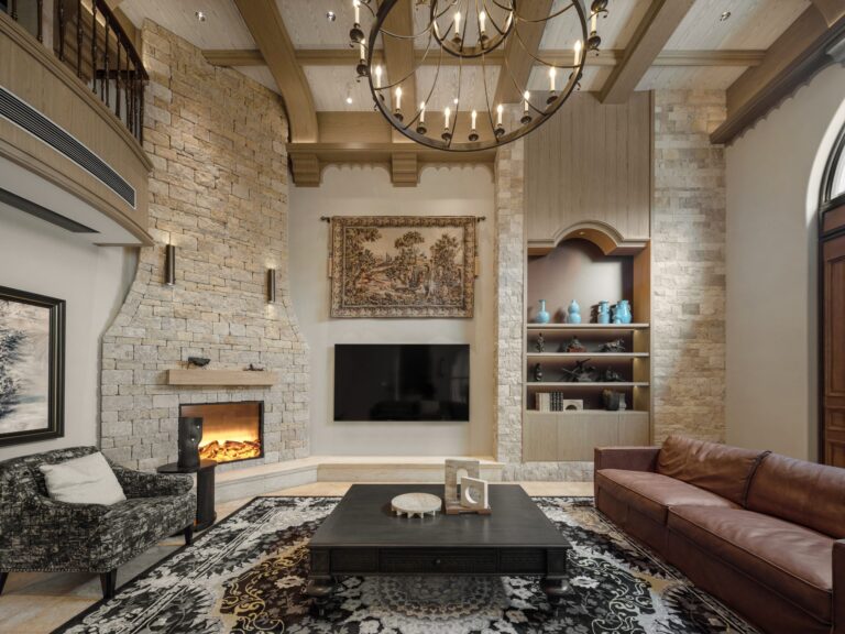 Luxurious living room with a stone fireplace, leather sofa, and ornate chandelier.