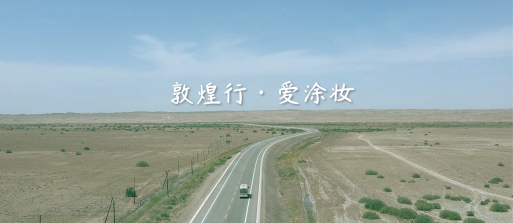 A white bus travels on a winding road through a vast, arid landscape under a clear blue sky.