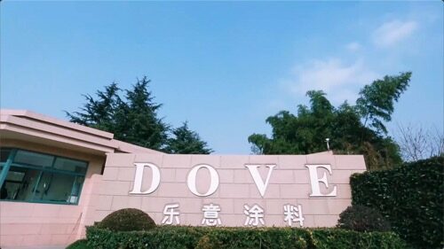 The Dove paint company building entrance features large white letters spelling DOVE above Chinese characters, set against a clear blue sky.