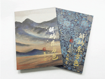 Two books, one with a misty mountain landscape and the other with a blue floral pattern, stand side-by-side.