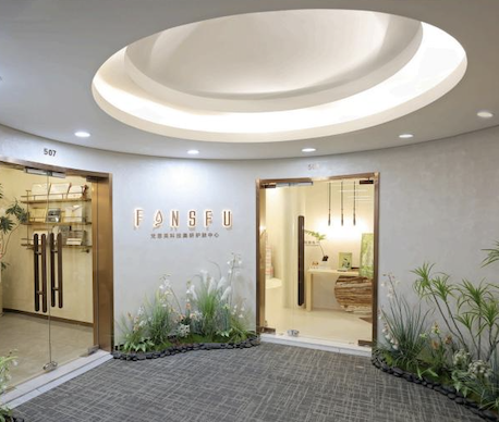 Modern spa entrance with elegant signage, glass doors, and lush greenery.