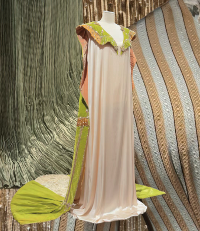 A flowing cream gown with a lime green, beaded collar and trim is displayed on a mannequin.