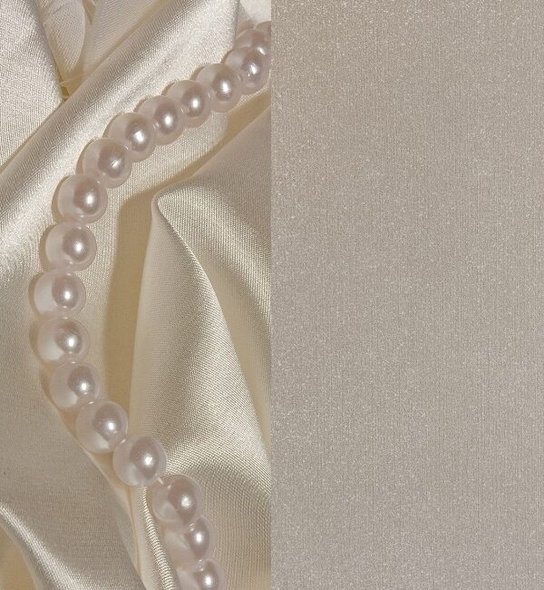 A strand of luminous pearls rests on draped satin fabric in a soft, neutral palette.