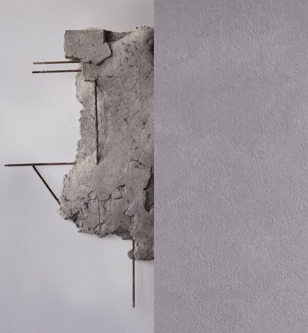 Rough concrete fragment with exposed rebar protrudes from a textured gray wall.