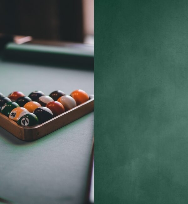 A rack of colorful billiard balls rests on a green felt pool table, ready for play.