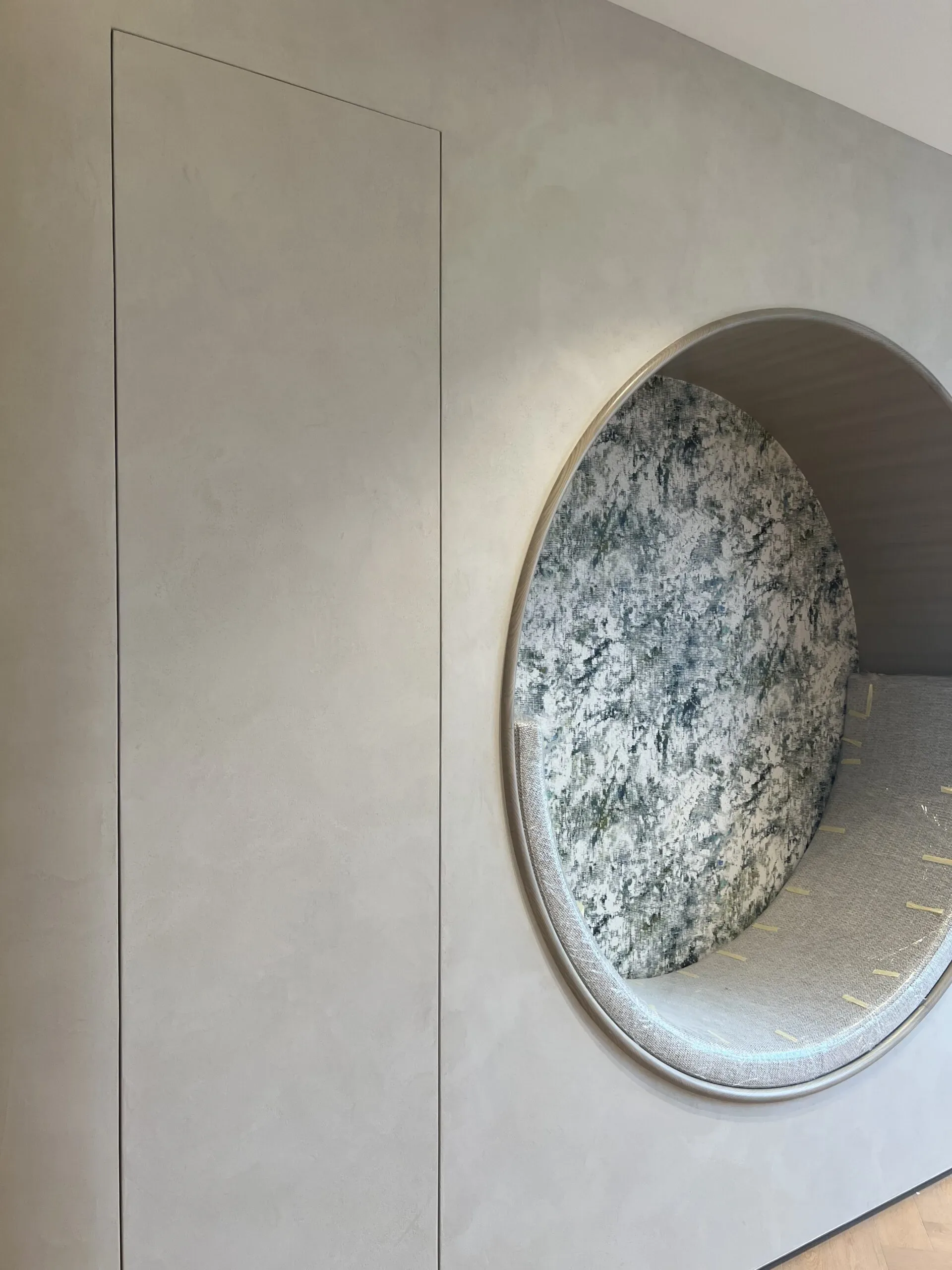 A circular alcove with leopard print wallpaper and a cushioned seat is set into a textured gray wall.
