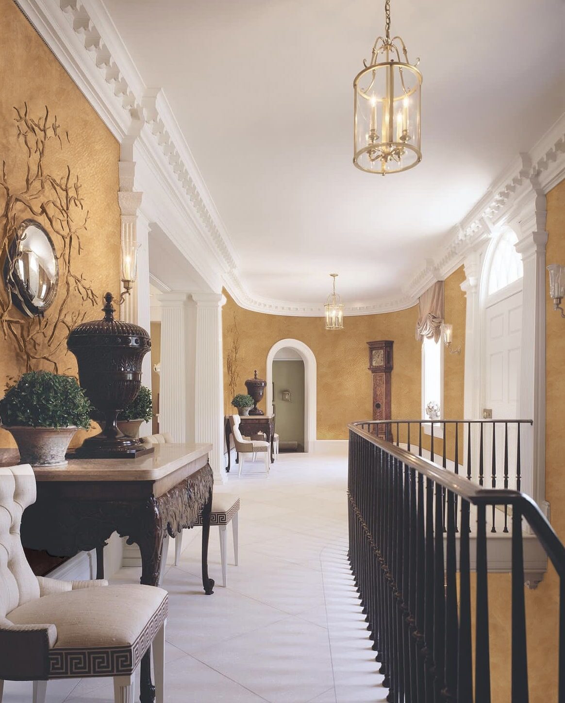 Elegant hallway with ornate console table, chairs, and a grandfather clock.
