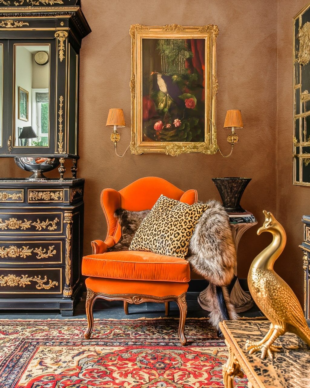 An ornate room features an orange velvet chair with a leopard print pillow and fur throw.
